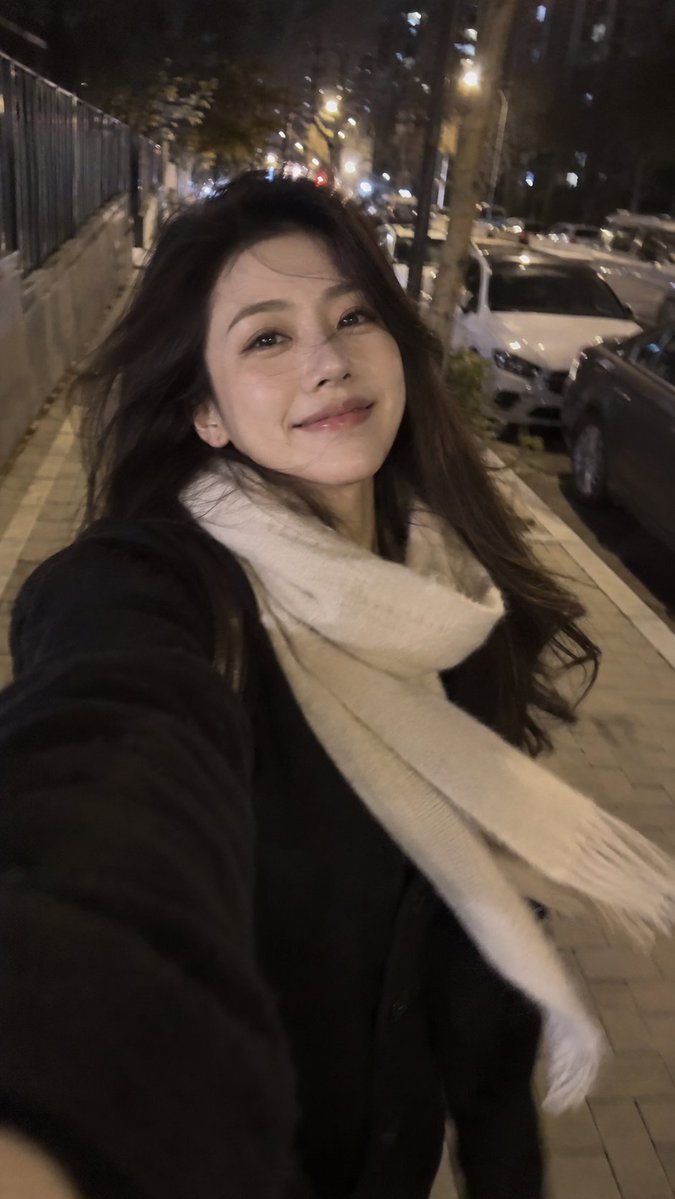Handheld Night Selfie Captures Windblown Hair Amid City Lights