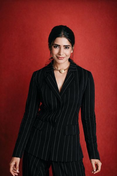 A woman in navy striped suit poses calmly in red studio