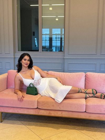 Young Indian woman lounges on pink velvet in white dress