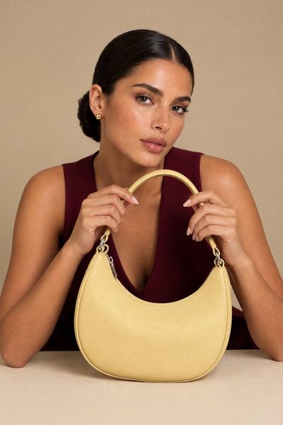 Elegant Woman Leans Forward Holding Custard Yellow Hobo Bag