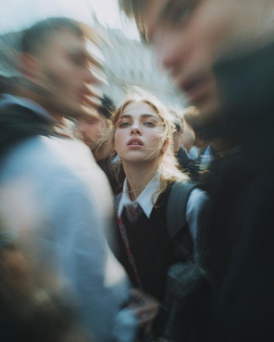 A woman in a school uniform turns startled under harsh flash
