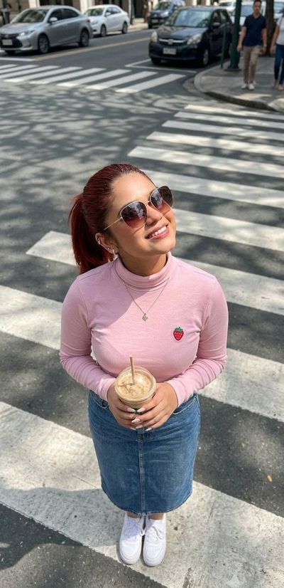Woman in pink T-shirt holds iced coffee at zebra crossing