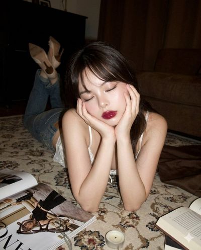 A woman rests on a carpet with closed eyes in dim warm light