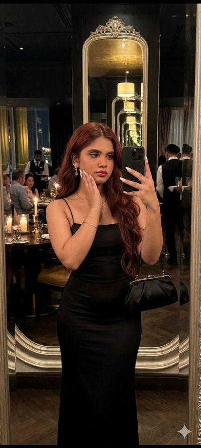 Elegant woman poses in mirror at a warm restaurant