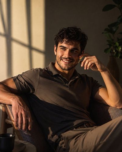Handsome man smiles in golden sunlight on charcoal lounge chair