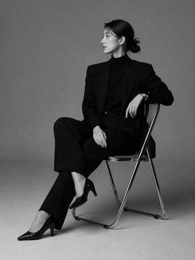 A Korean woman in a black blazer poses sharply in profile