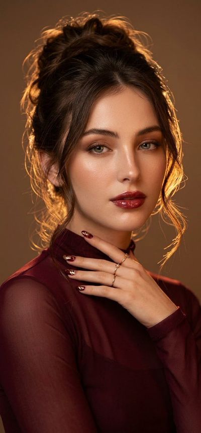 Woman in burgundy sheer outfit poses with golden rim light portrait