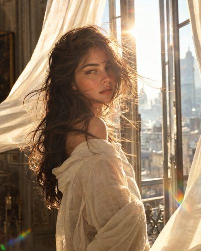 Sunlit woman with windblown hair gazes back at camera