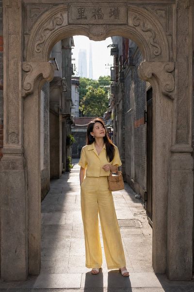 Young woman stands beneath shikumen arch in morning light