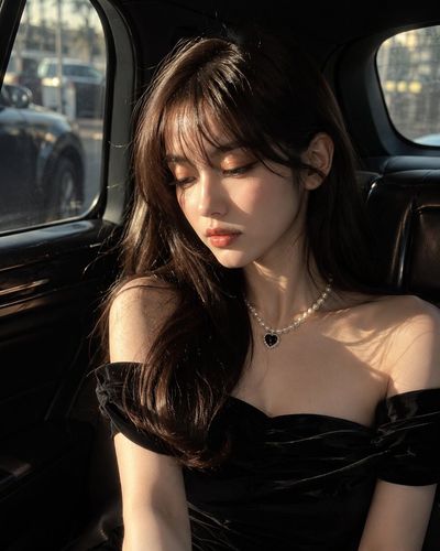 Woman in black dress sits in luxury car with golden sunlight