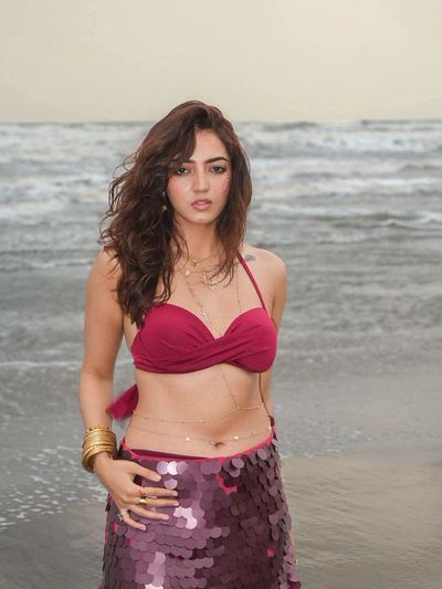 Woman in magenta bikini poses on a misty beach