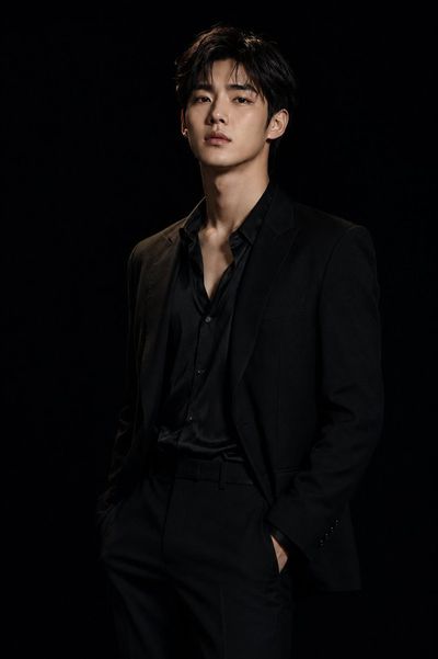 Korean man in sleek black suit poses in dramatic studio light