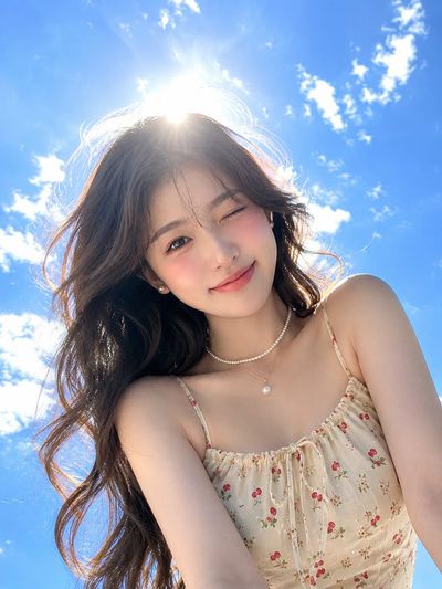 Young woman winks playfully under a bright summer sky