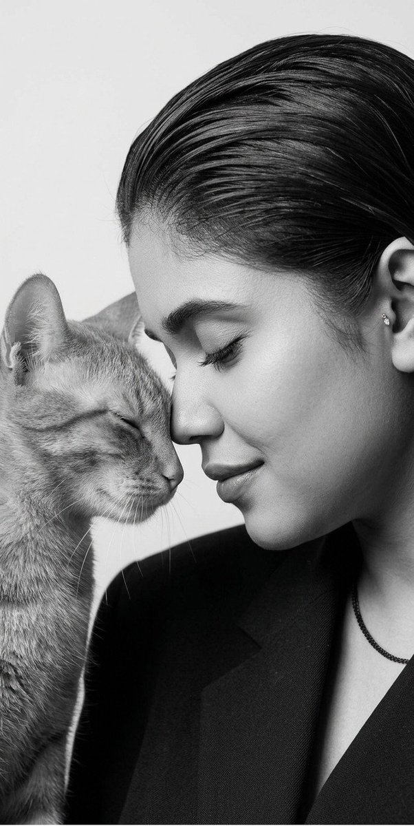A woman touches foreheads with a black cat in monochrome studio