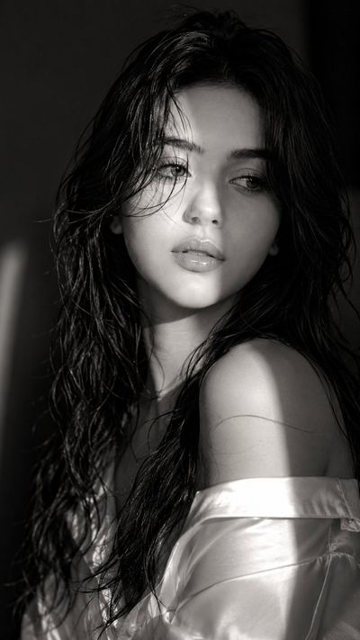 A mysterious woman in monochrome light glances away with glossy lips.