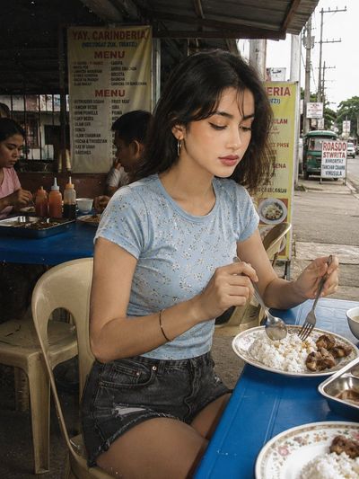 Young woman enjoys a quiet meal at a bustling roadside diner