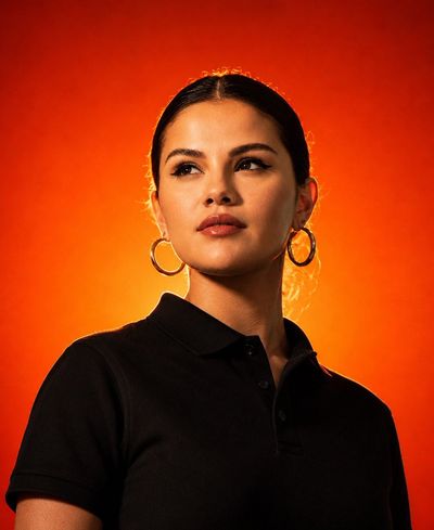 Confident model in black polo glows against fiery orange background