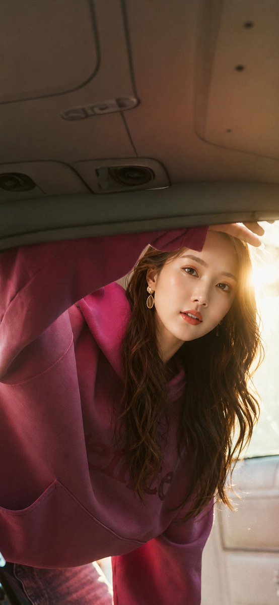 Woman leans into car trunk as golden sunlight streams through