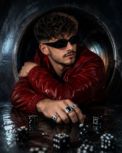 A man in a red jacket stands inside a dark circular tunnel