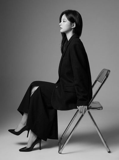 A Korean model in profile wears a tailored blazer and flowing skirt.