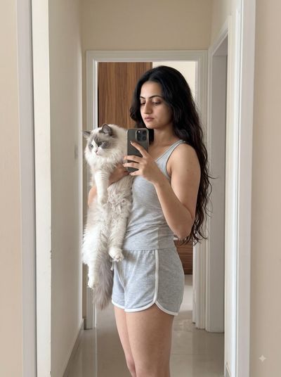 Woman cradles fluffy Ragdoll cat while taking a mirror selfie