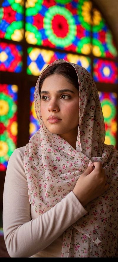 Woman in floral scarf poses near stained-glass window