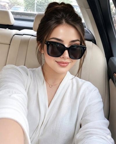 Young woman in black sunglasses poses inside luxury car interior