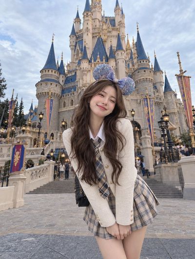 Young woman poses excitedly before grand fairytale castle in candid travel photo
