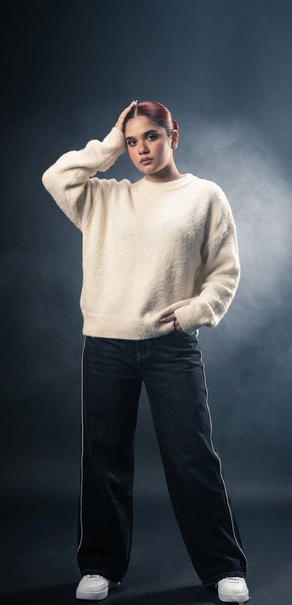 Oversized cream sweater meets relaxed high-fashion stance in studio