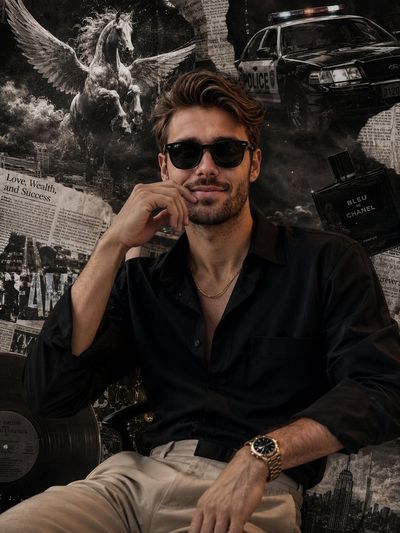 Stylish man in black sunglasses poses against grunge collage background