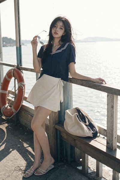 K-pop idol leans against a weathered ferry railing in summer breeze.