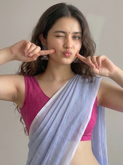 Young Indian woman winks playfully in hot pink choli and lavender saree