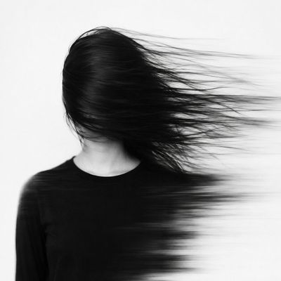 A woman's face dissolves into sweeping black hair strands