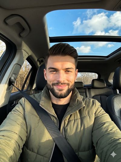 Young man in olive jacket poses confidently inside a sunlit car