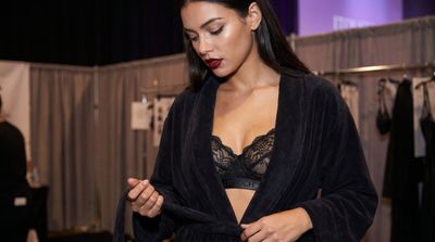 Model walks toward lavender backdrop with confident over-the-shoulder gaze