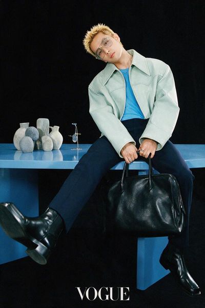 Fashion Model Sits on Glossy Blue Table with Sculptural Ceramics