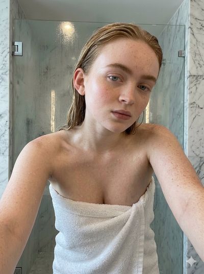 Woman with wet skin after shower poses for close-up selfie in bathroom