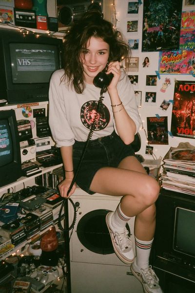 A woman chats on a rotary phone in a nostalgic 90s bedroom