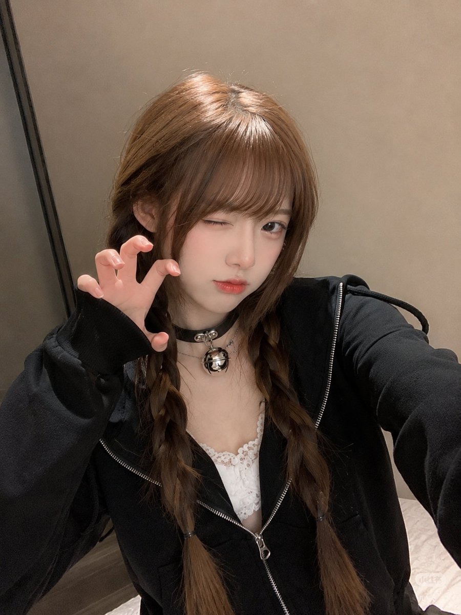 East Asian woman in black hoodie stares calmly into phone camera