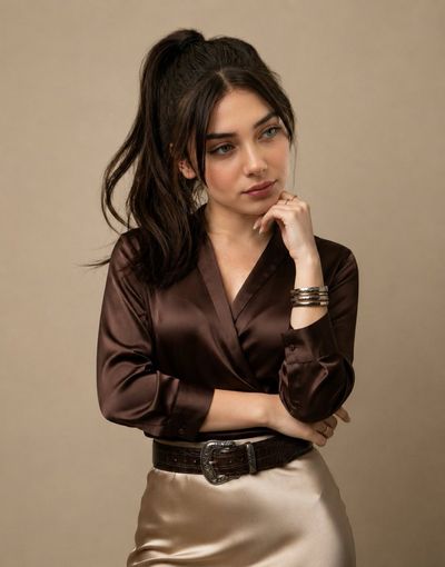 Elegant woman in chocolate satin poses against warm beige studio backdrop