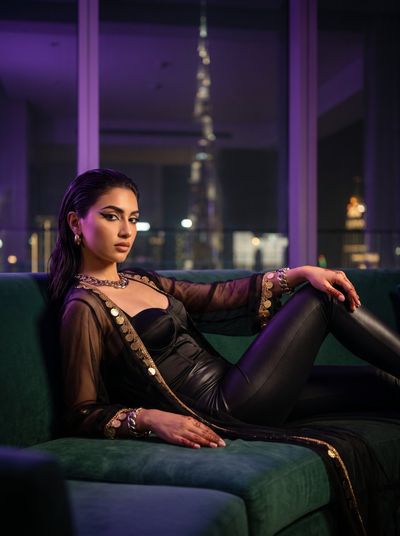 Arab Creative Director Reclines on Emerald Sofa in Dubai Penthouse at Night