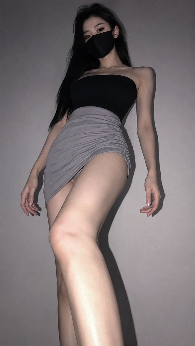 A woman in black mask gazes downward from low angle