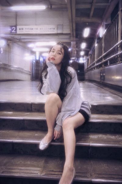 A woman sits on station steps in glowing cinematic light