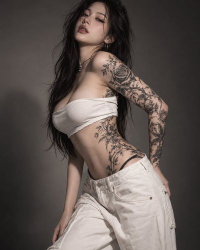 Sensual tattooed woman poses with arched back and half-closed eyes