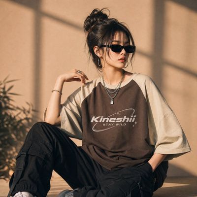 Young woman in oversized chocolate tee poses in sunlit studio