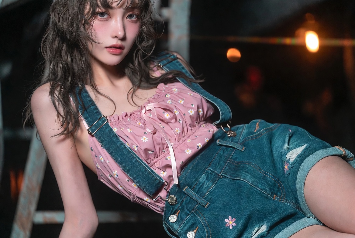 Japanese woman in denim shorts poses seductively in dim industrial light.