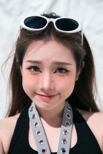 Young woman with sunglasses on head smiles playfully in black top