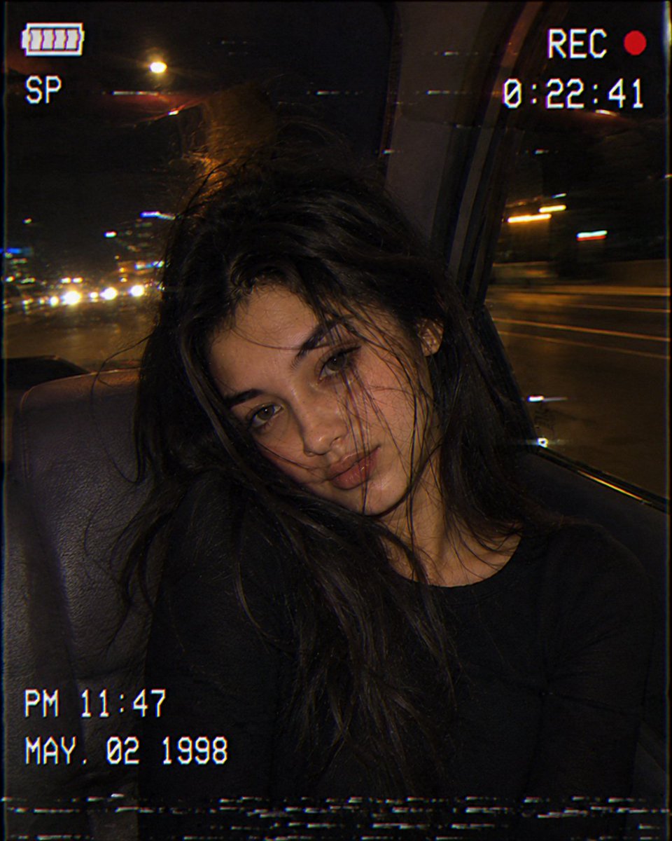 A woman rides in a 1998 car with neon lights streaming by