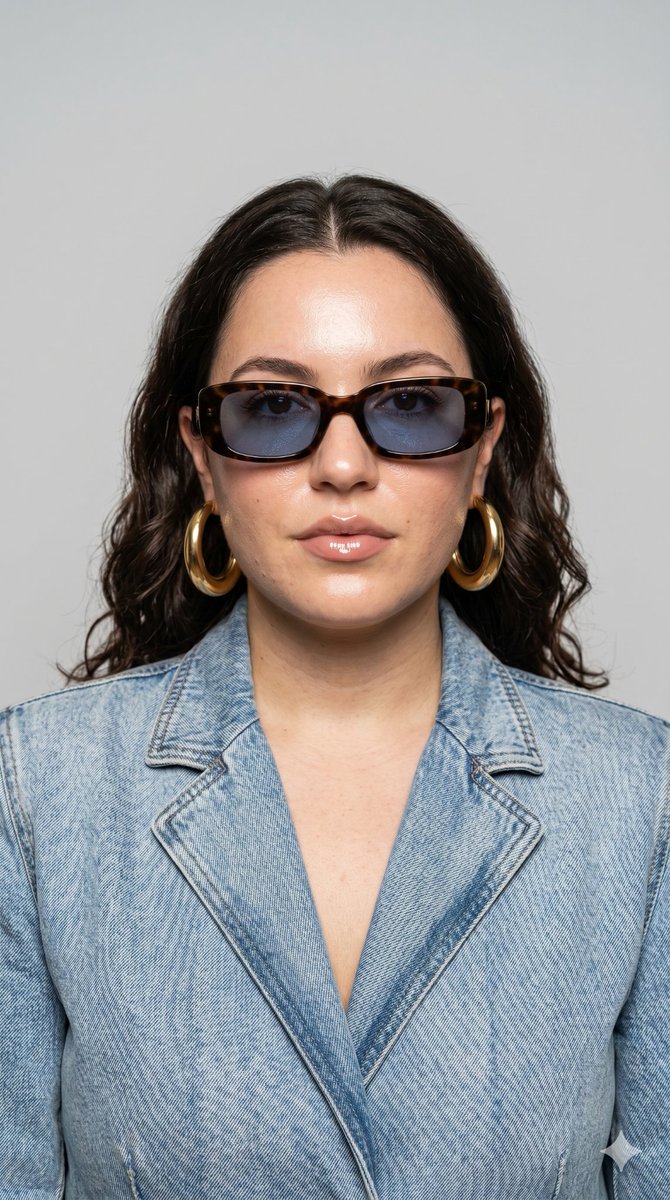 A confident model in retro sunglasses poses for editorial fashion portrait