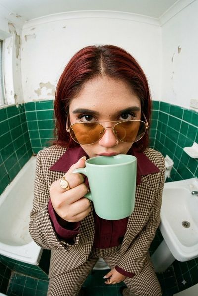 Woman with mint mug dominates warped green bathroom in editorial shot